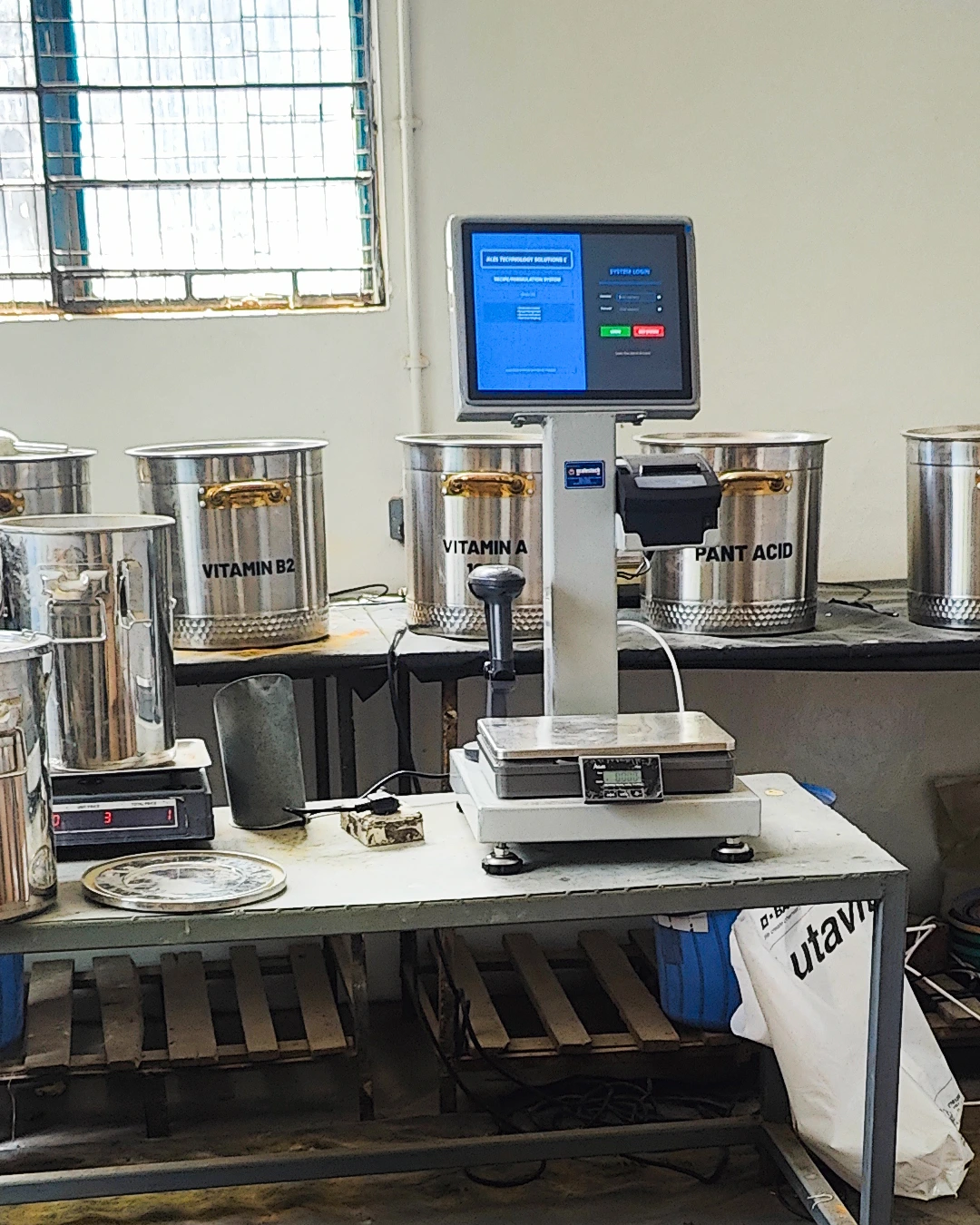 A production operator uses the barcode-based ingredient verification system at a platform weighing scale, ensuring every ingredient is correctly identified and measured before entering the batch — reducing errors and maintaining compliance across high-volume manufacturing runs